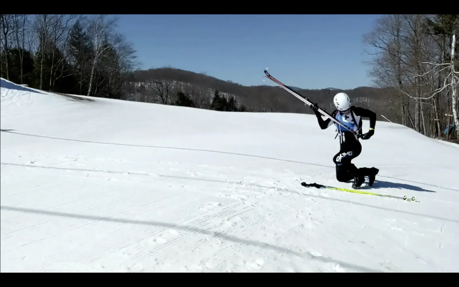 An image of a skimo racer holstering his skis during the skin-to-boot transition