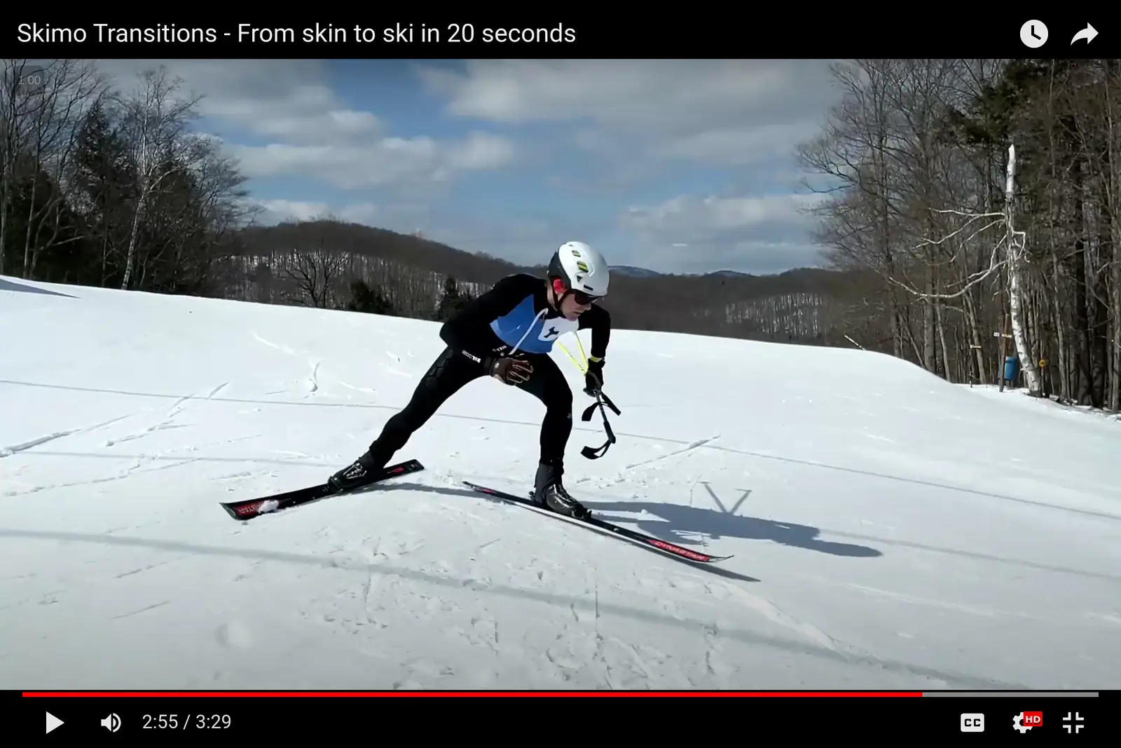 An image of a skimo racer just exiting a transition zone, both poles in one hand